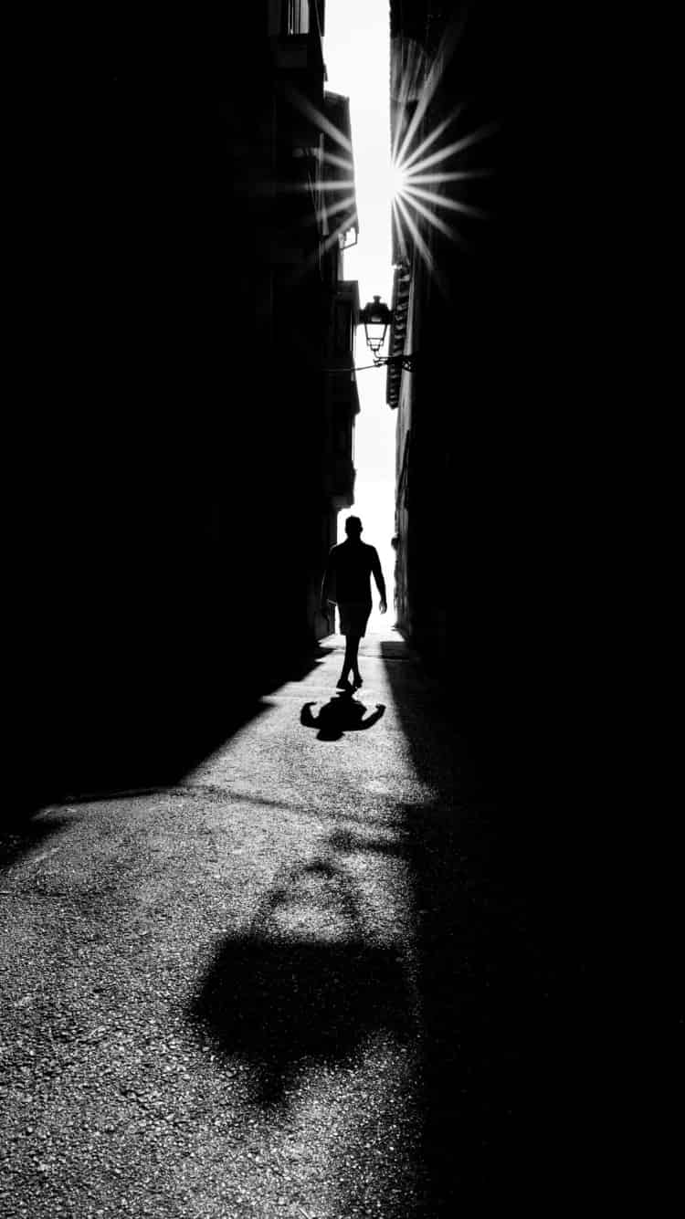 narrow light - figure mid-stride in sliver of light in palma old town alley