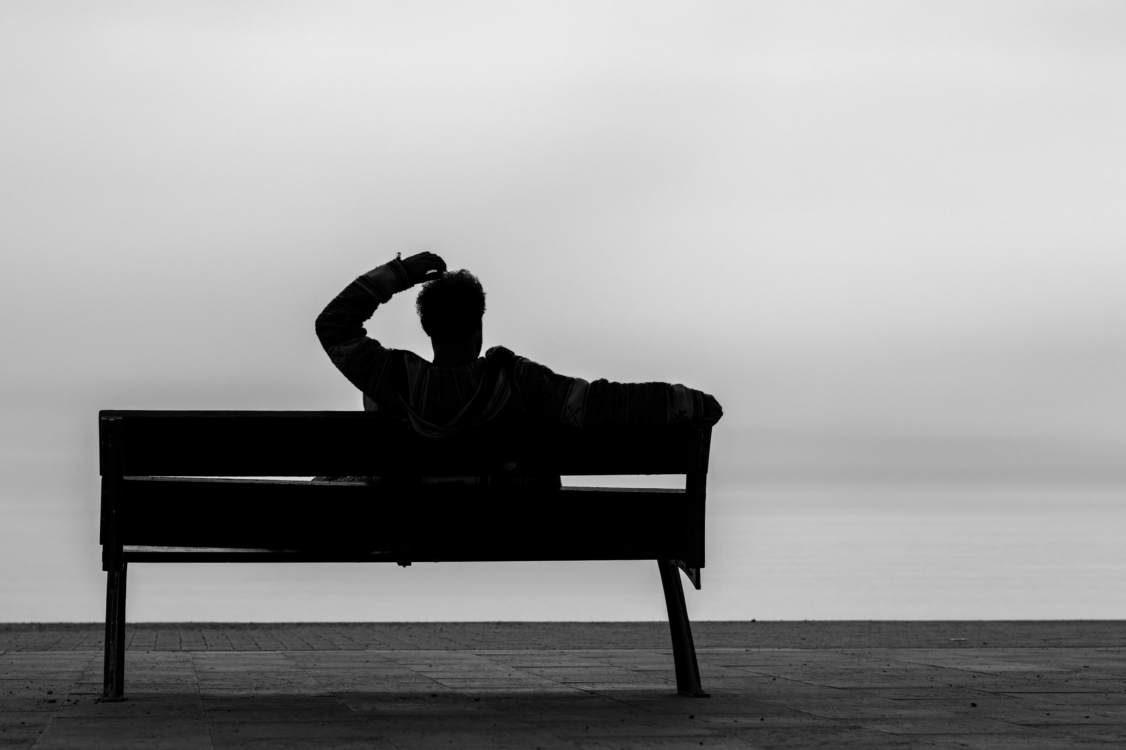 Silhouette resting on a wooden bench by the sea